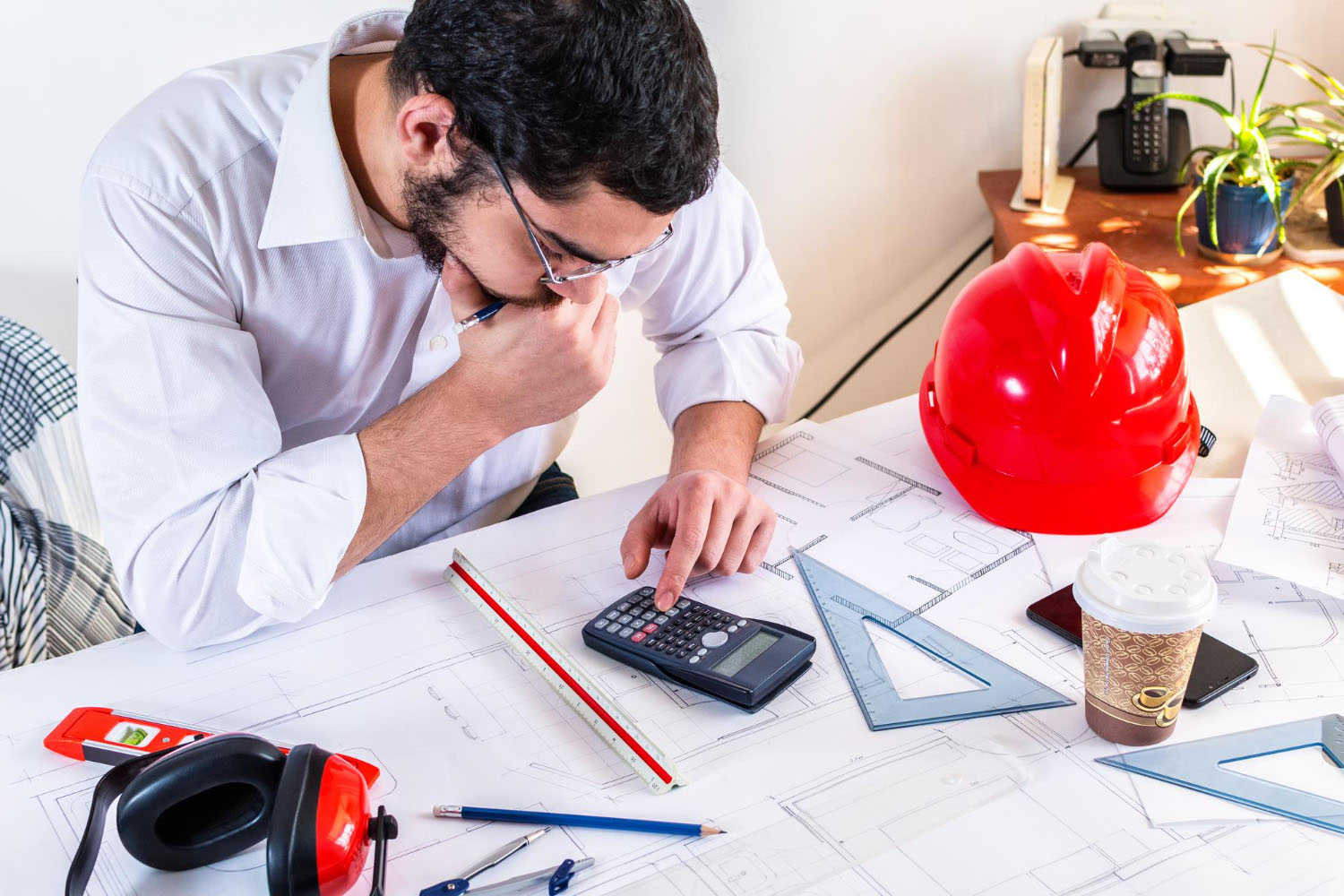 Ingegnere calcola misure su progetti architettonici