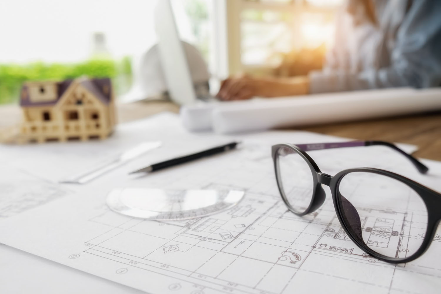 Occhiali su planimetria architettonica con modellino di casa
