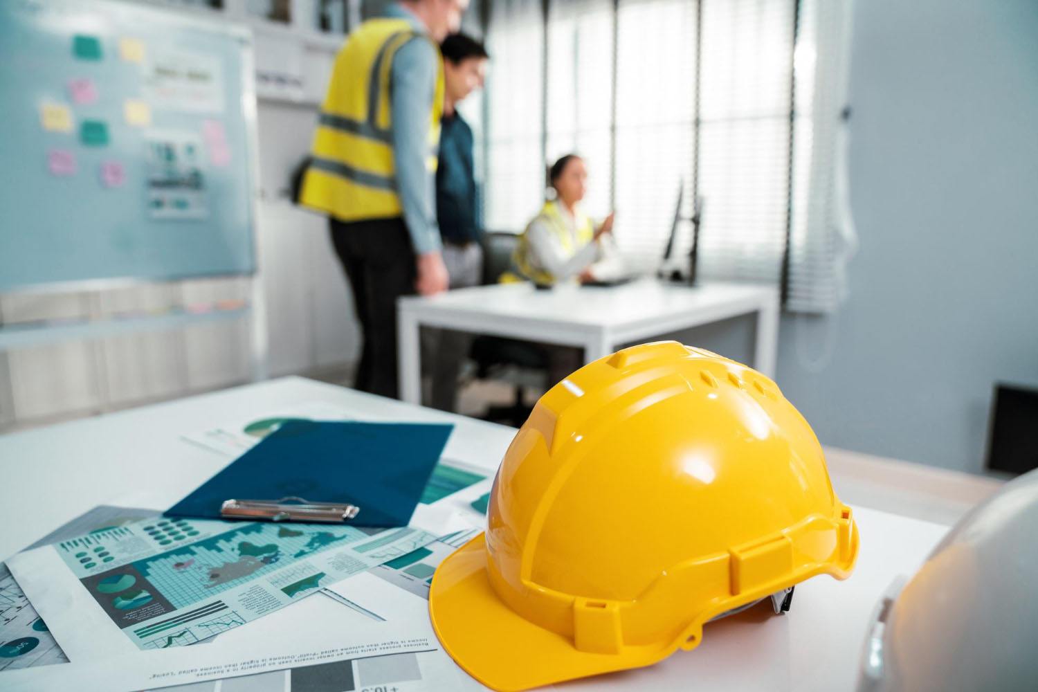 Casco giallo su tavolo durante riunione di cantiere